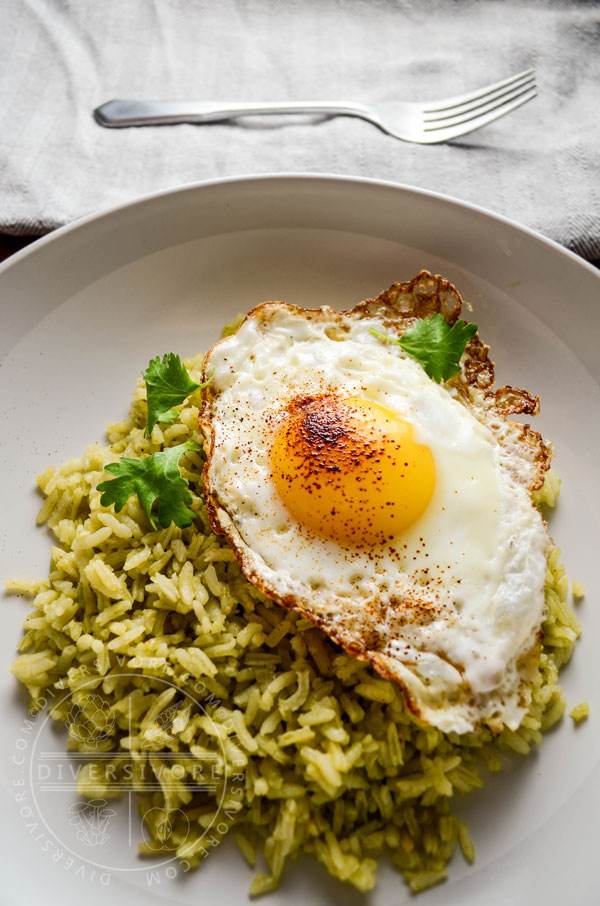 Green Rice (Arroz Verde) on a large white plate, topped with a fried egg dusted with ancho chili powder.