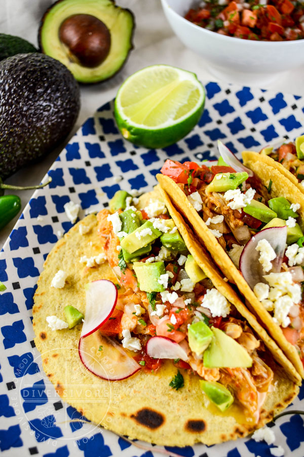 Chicken tinga in tacos with avocado, radish, cotija, and salsa