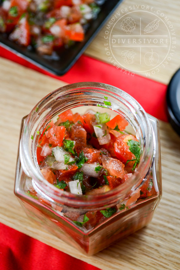 Pico de Gallo in a small hexagonal glass jar against a wood backdrop