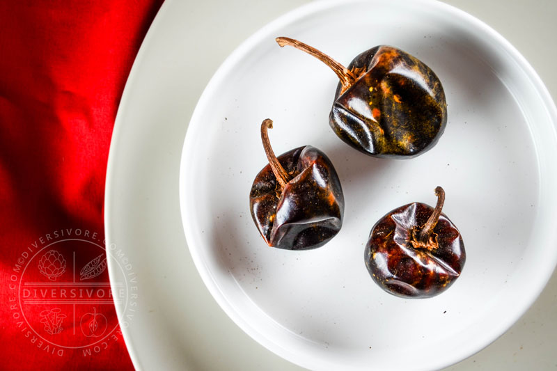 Three cascabel chilies on a white plate