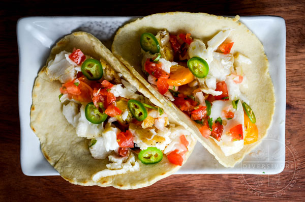 Halibut escabeche served in two tacos on a rectangular plate