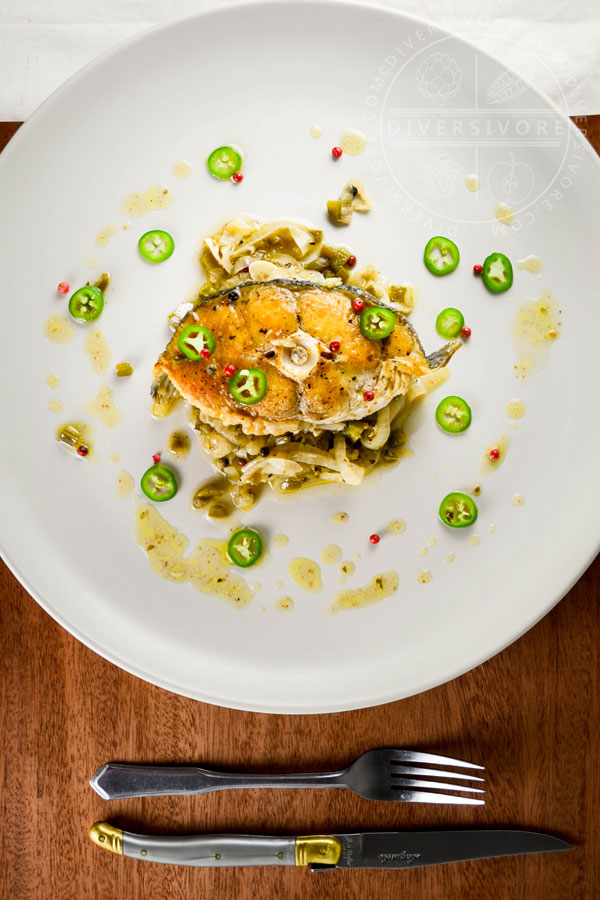 Halibut escabeche with onions and fresh jalapeño peppers on a large white plate