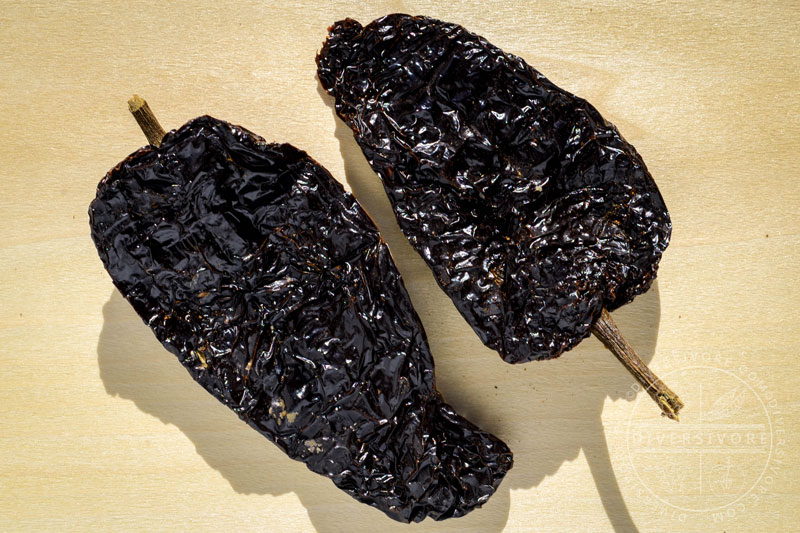 Two mulato chilies on a wooden backdrop