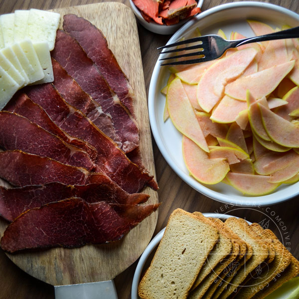 A charcuterie board with bison bresaola and pink pearl apples