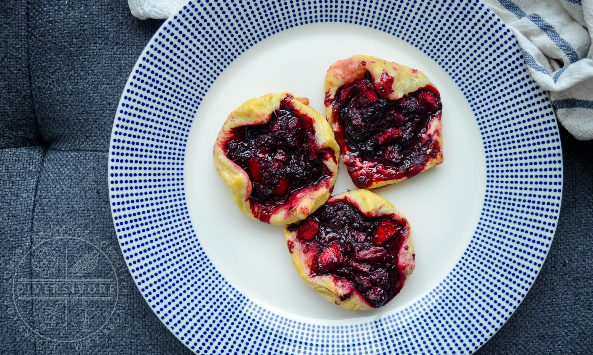 Dewberry and apple puff pastry tarts on a white plate with blue dots