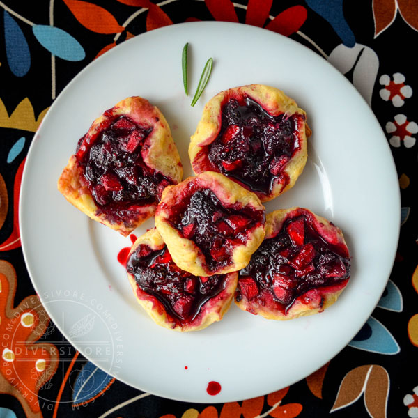 Dewberry and apple puff pastry tarts on a white plate against a multicoloured backdrop