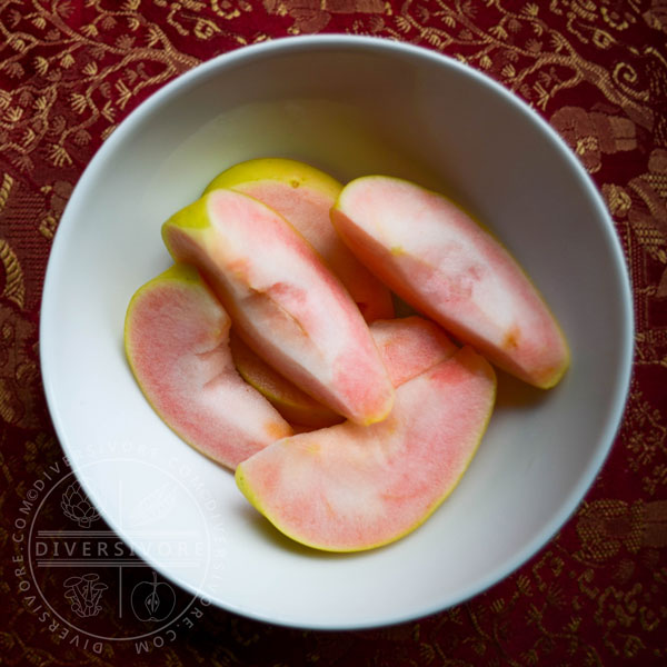 Sliced pink pearl apples in a white bowl