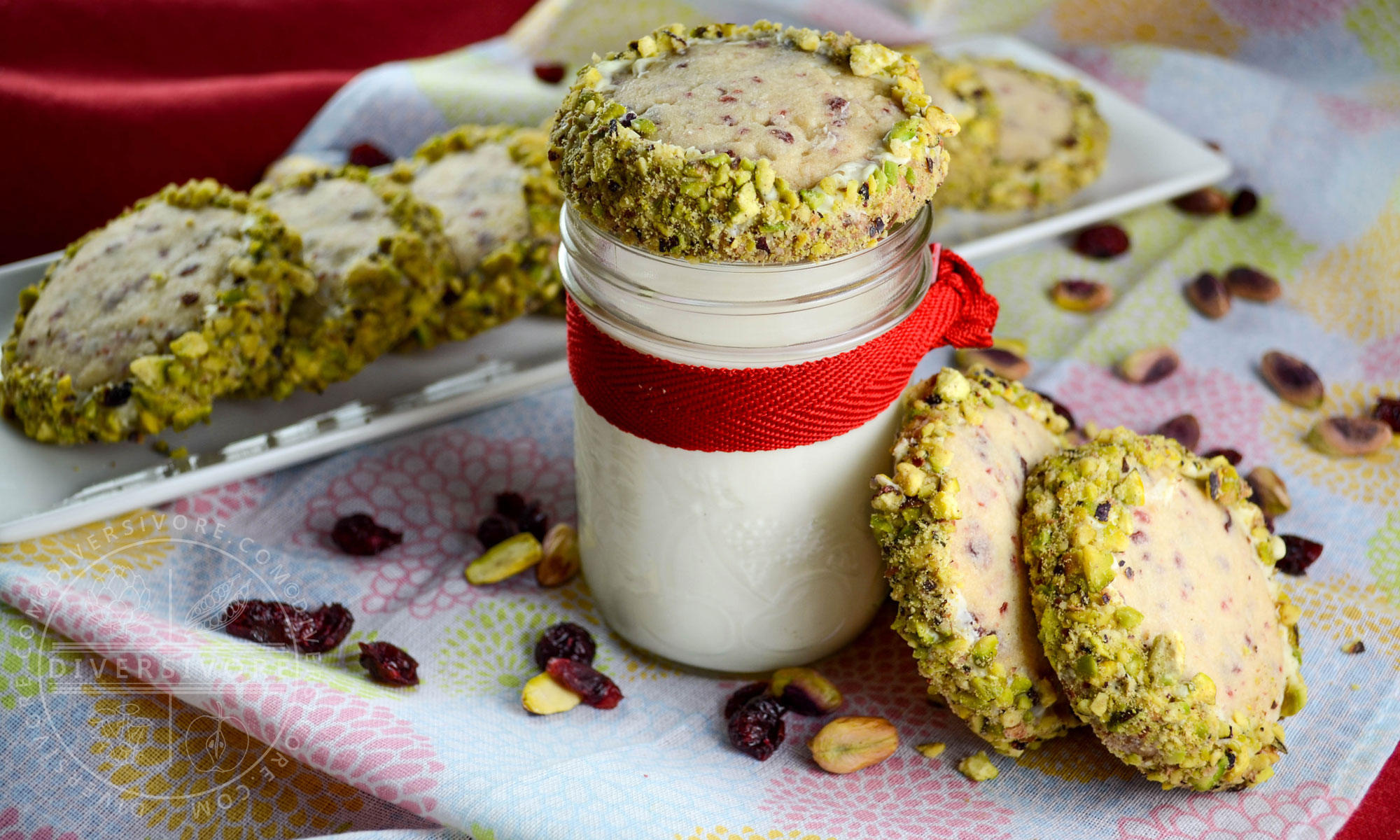 Cranberry shortbread cookies rolled in white chocolate and pistachios, served with a glass of milk tied with a red ribbon