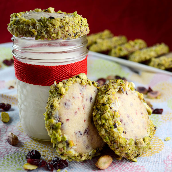 Cranberry shortbread cookies rolled in white chocolate and pistachios, served with a glass of milk tied with a red ribbon