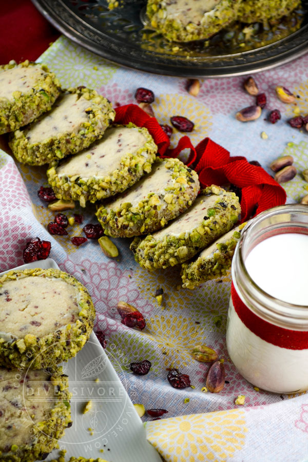 Cranberry shortbread cookies rolled in white chocolate and pistachios, served with a glass of milk tied with a red ribbon