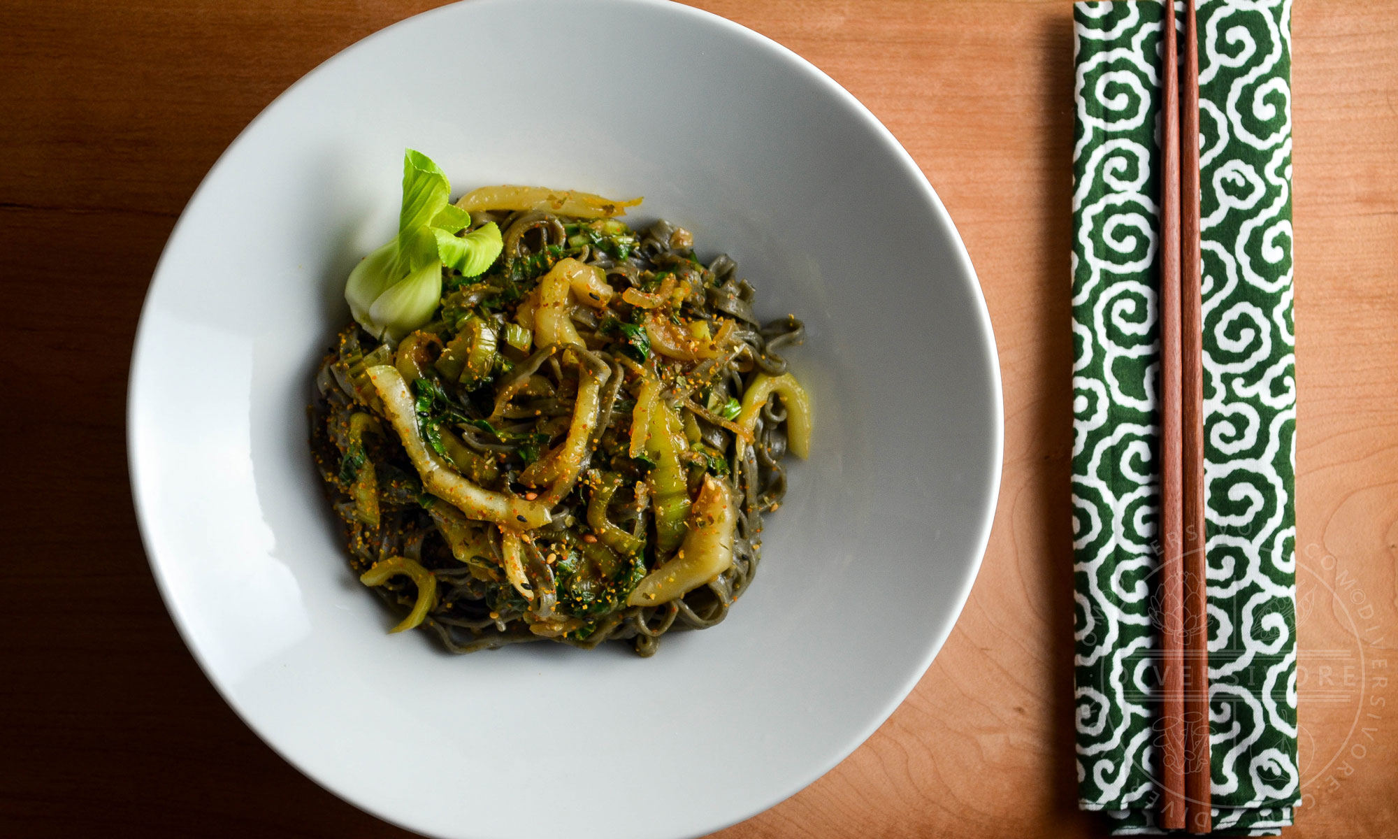 Garlic and lemon bok choy with black sesame noodles in a large white bowl