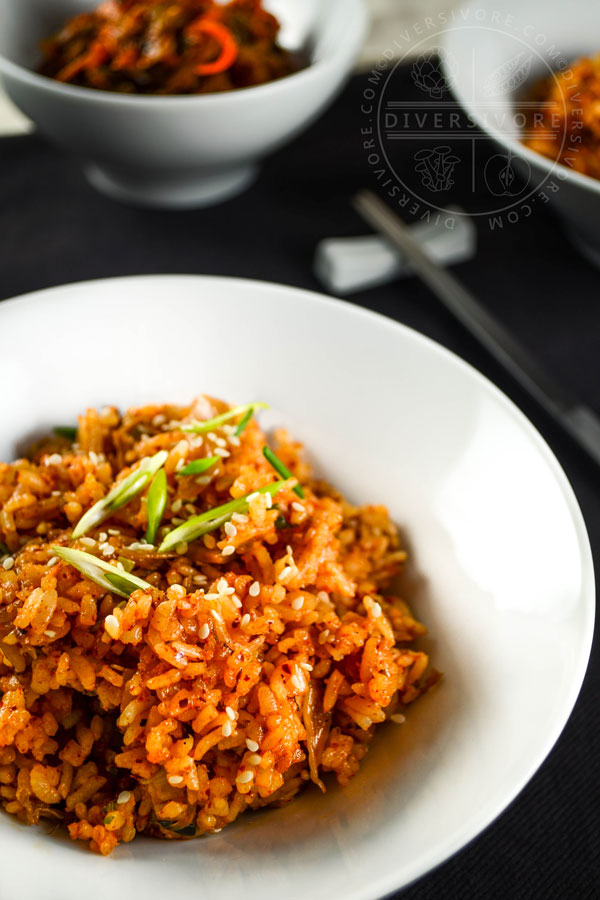 Kimchi fried rice in a small white bowl, topped with sesame seeds and scallions