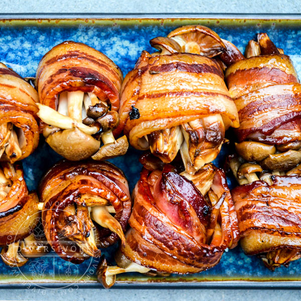 Shimeji mushrooms wrapped in bacon and brushed with tare sauce, served on a blue plate