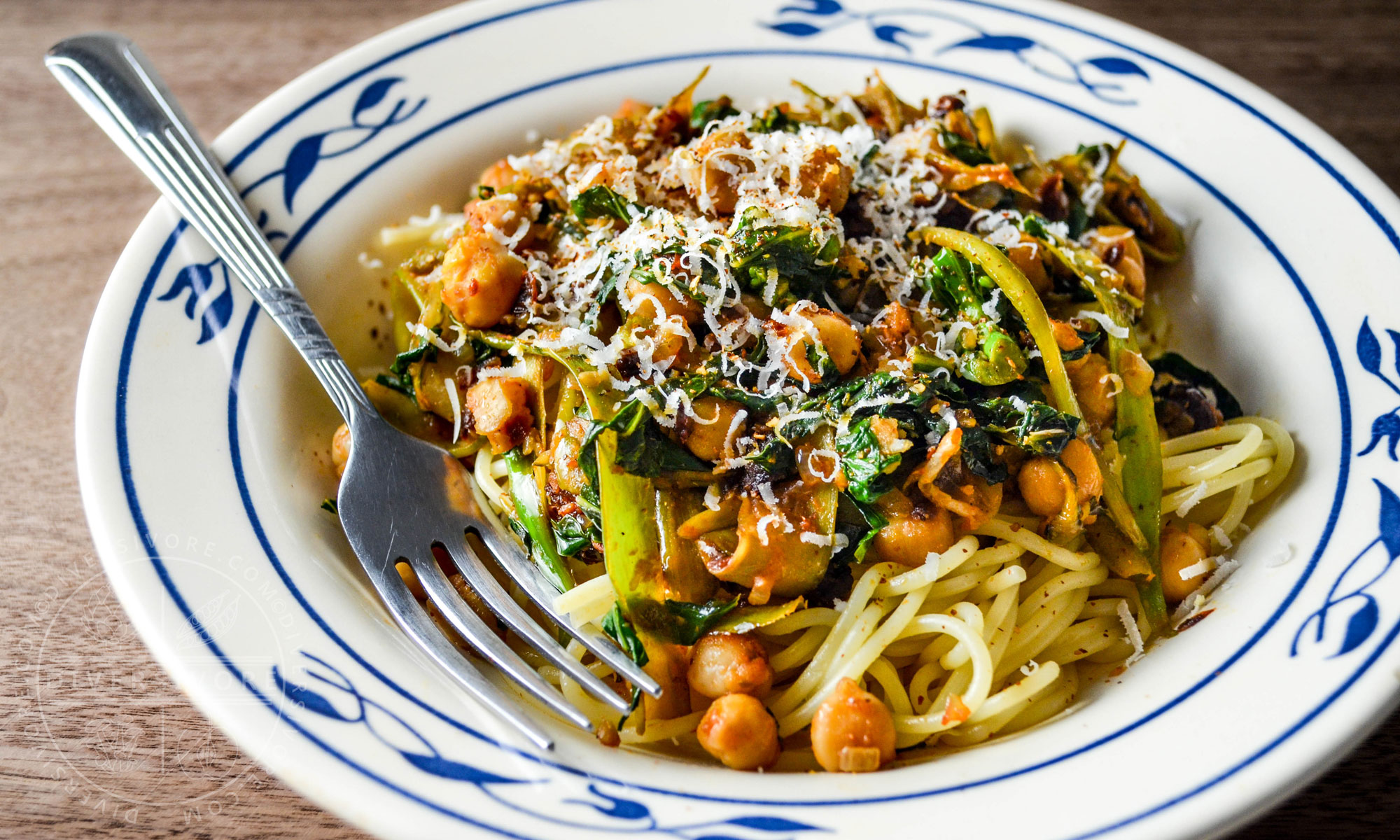 Chickpea and Gai Lan Spaghettini in a blue and white bowl with a fork