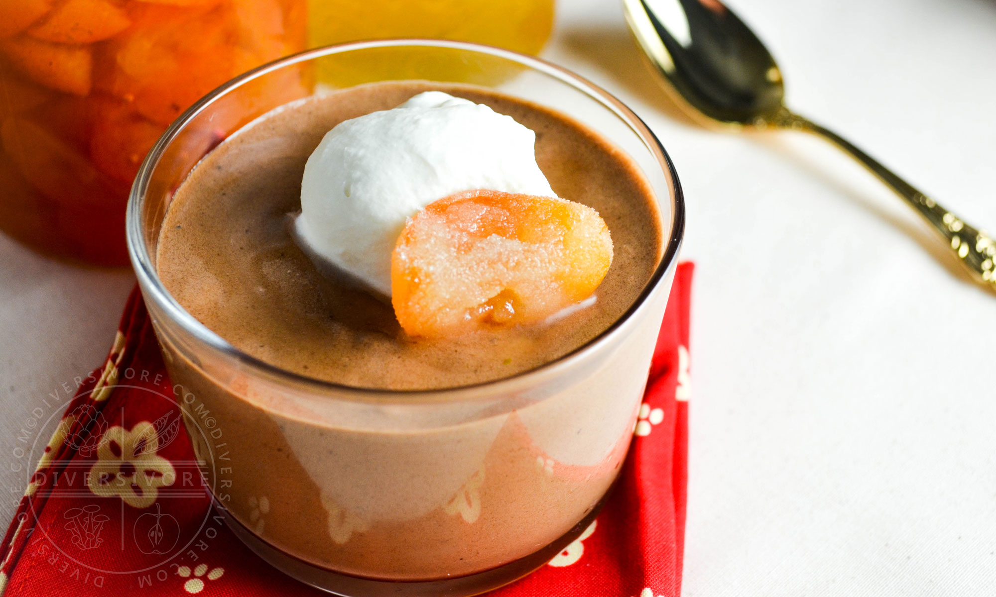 Chocolate mousse with candied kumquats and whipped cream in a glass with a gold spoon