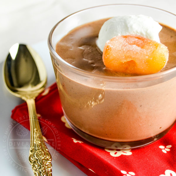 Chocolate mousse with candied kumquats and whipped cream in a glass with a gold spoon