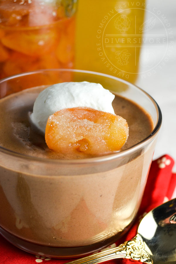 Chocolate mousse with candied kumquats and whipped cream in a glass with a gold spoon