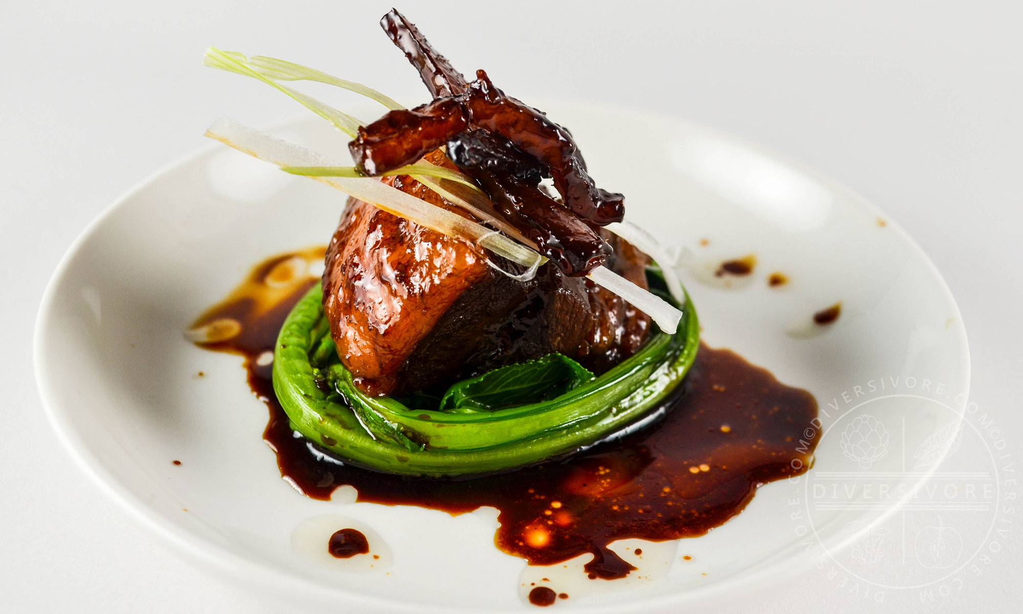 Dongpo Rou (Chinese red-cooked pork belly) with yu choy on a white plate