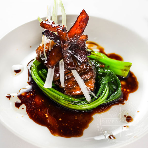 Dongpo Rou (Chinese red-cooked pork) with yu choy on a white plate