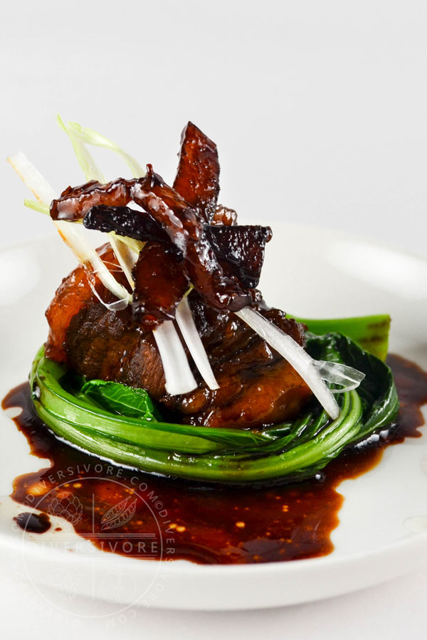 Dongpo Rou (Chinese red-cooked pork) with yu choy on a white plate