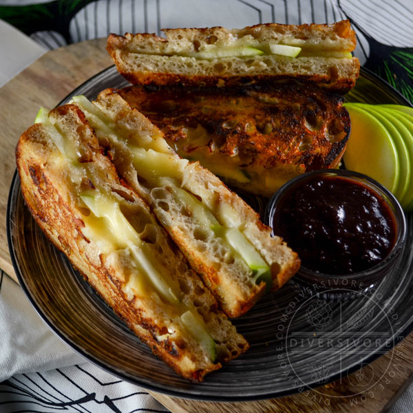 Granny smith grilled cheese sandwiches, cut in half and served with plumcot ketchup on a black and white patterned plate