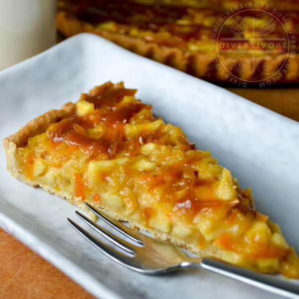 A slice of kumquat apple tart with whiskey caramel on a rectangular plate with a small dessert fork