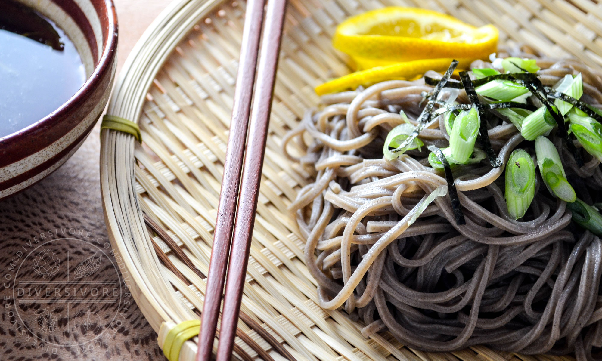Mandelo Zaru Soba (cold buckwheat noodles with a mandelo dipping sauce) on a straw plate with chopsticks