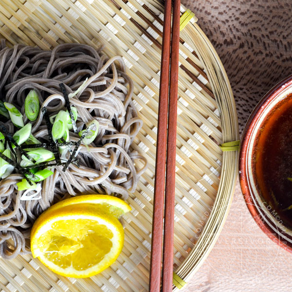 Mandelo Zaru Soba on a Japanese zaru (draining basket), topped with nori and scallions, and served with tsuyu (dipping sauce).