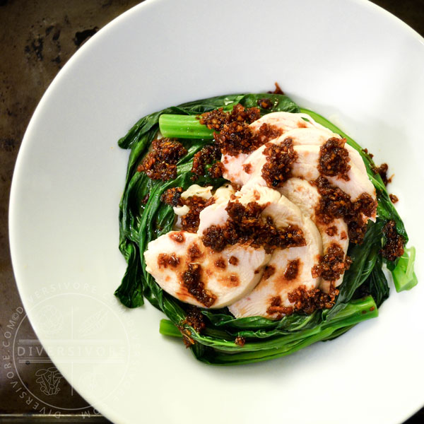 Hakka poached chicken with garlic and ginger, served with yu choy in a white bowl