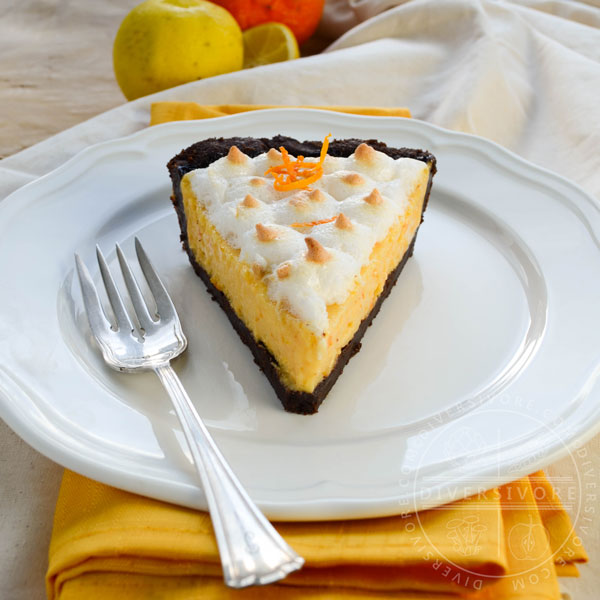 A slice of seville orange pie with meringue and a chocolate graham wafer crust, served on a white plate with a silver dessert fork