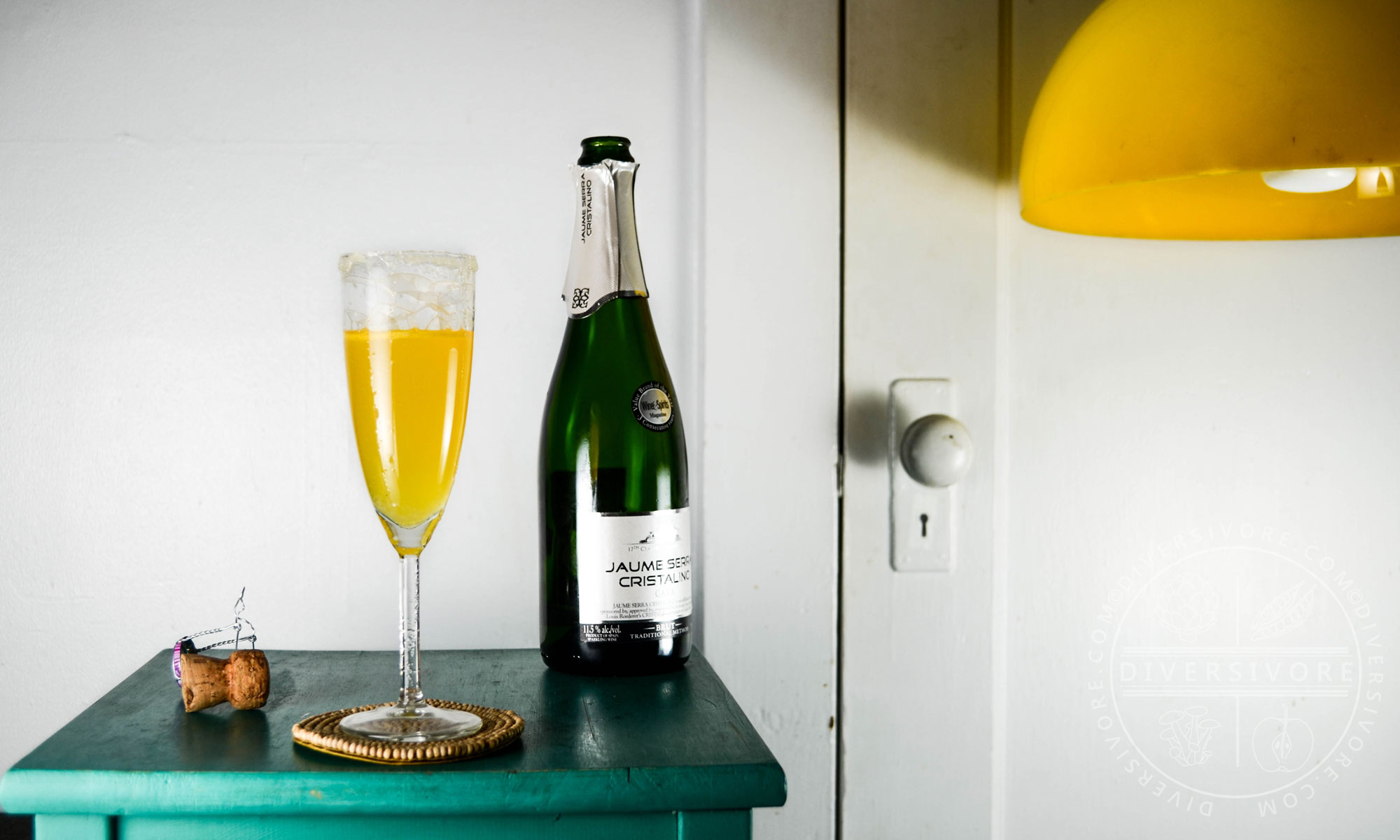 Sparkling Saffron Cocktail with a bottle of cava on a turquoise table