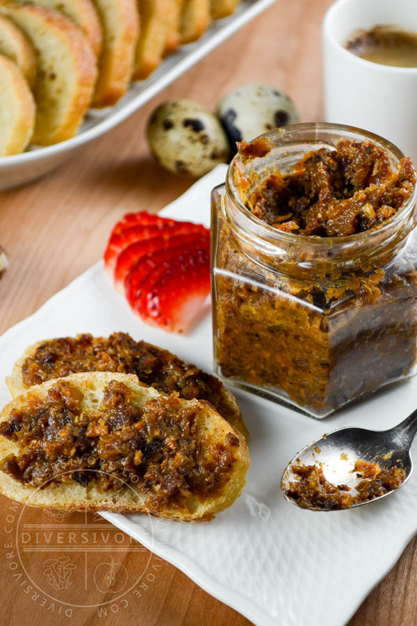 Bacon marmalade in a hexagonal glass jar with a spoon, bread, strawberries, and scattered quail eggs