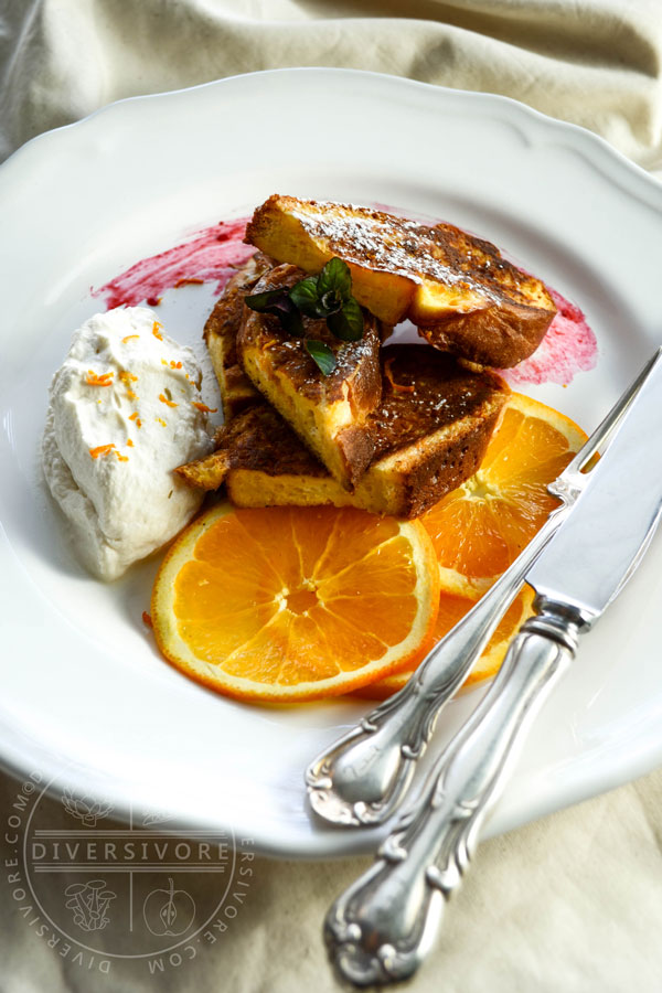 Seville Orange French Toast on a white plate with orange slices and maple whipped cream