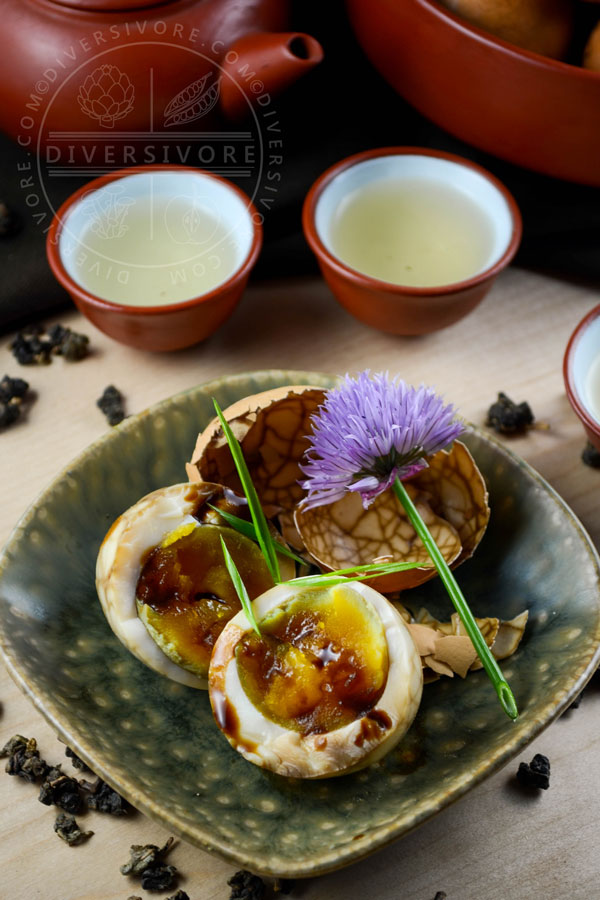 Taiwanese tea eggs in a small ceramic dish with a chive blossom.