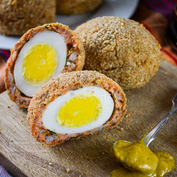 West Coast scotch eggs made with fresh salmon sausage on a wood platter with mustard