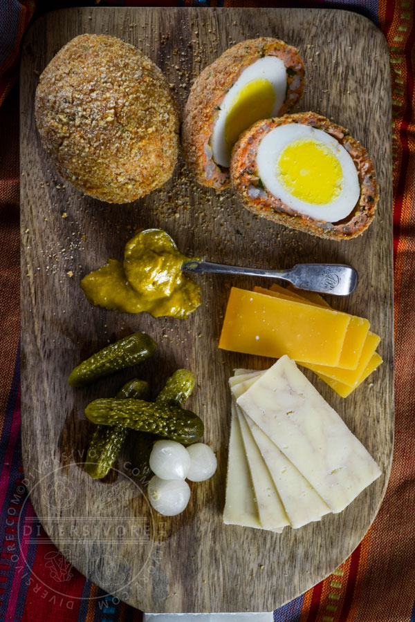 West Coast scotch eggs made with salmon sausage, served with cheese, pickles, and mustard