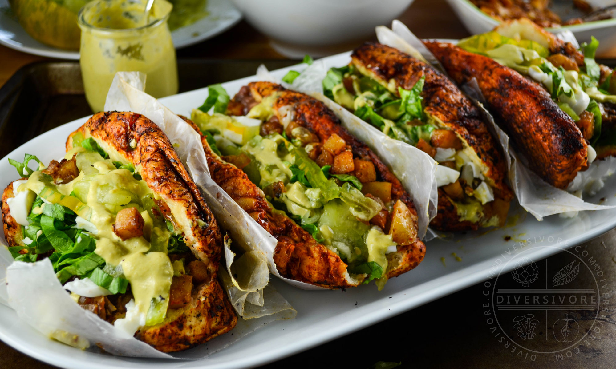 Four pambazos con huevos (Mexican sandwiches made with guajillo sauce-soaked buns and filled with eggs, crispy potatoes, and a creamy egg salsa verde).