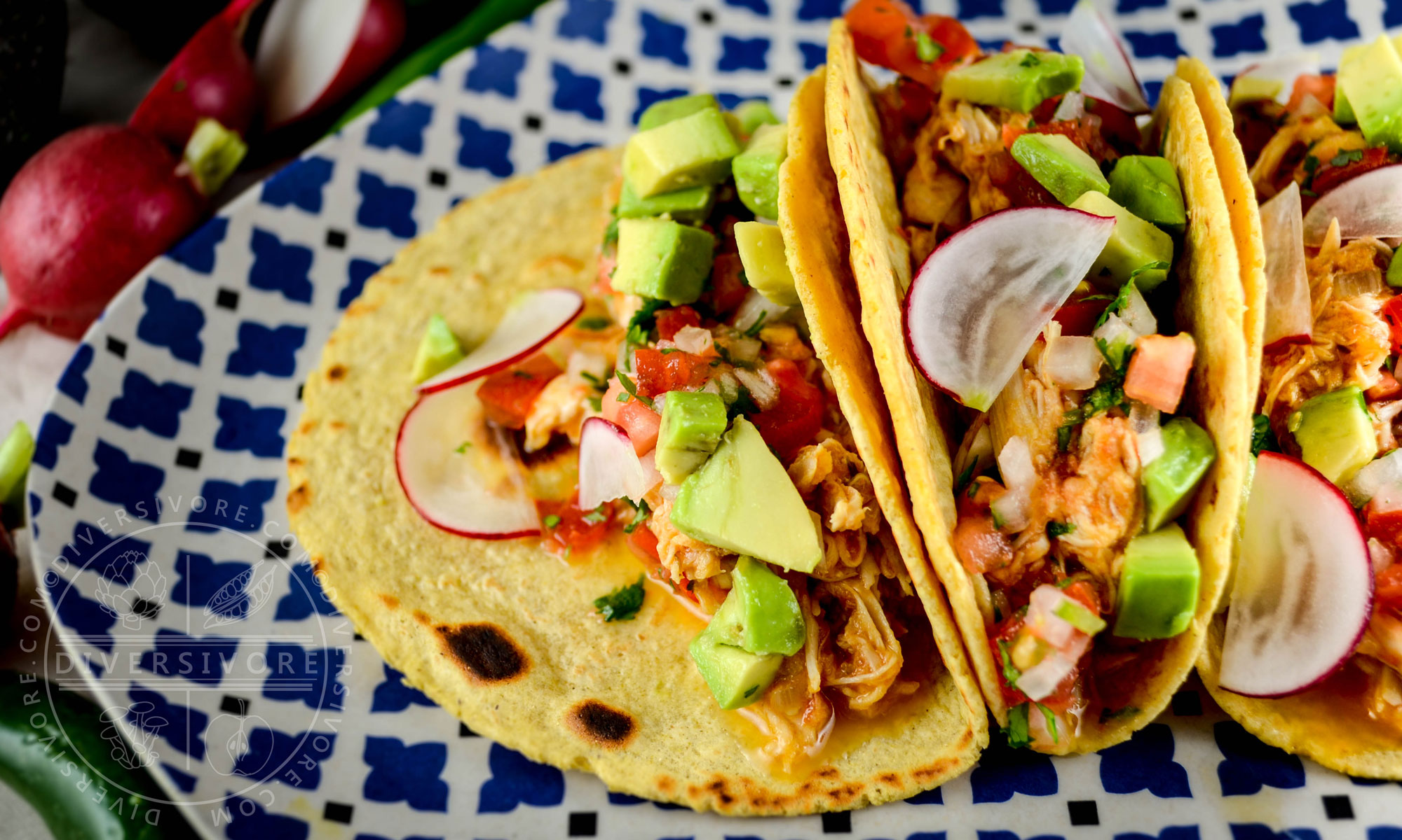 Chicken tinga in tacos with avocado, radish, and salsa