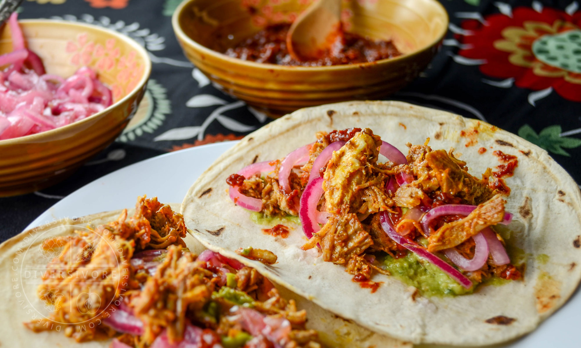 Puerco Pibil (aka cochinita pibil) served with pickled onions and guacamole in tortilla shells