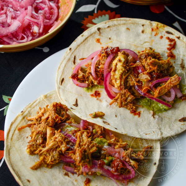 Pressure-cooked Puerco Pibil with pickled onions served in tortillas, flanked by smoky dried chili salsa