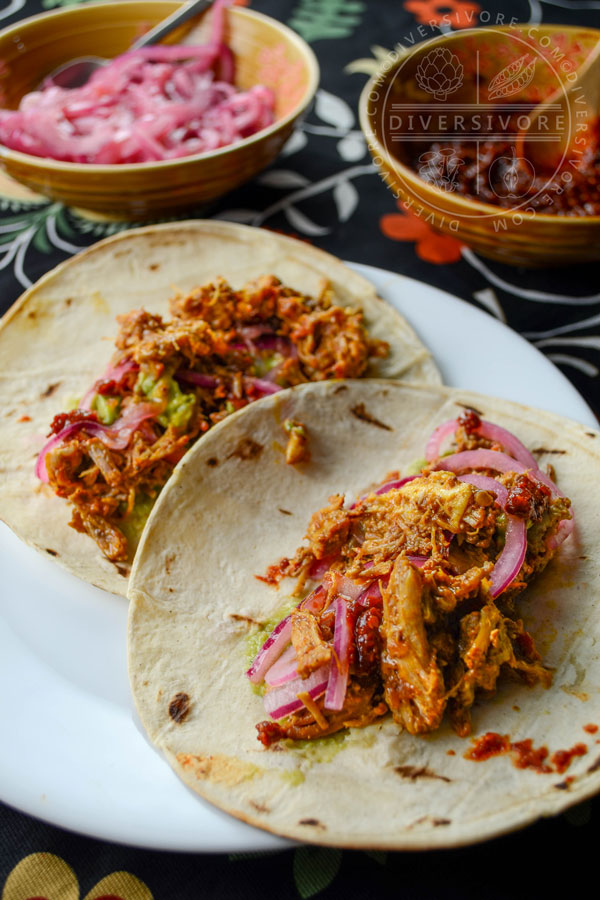 Pressure-cooked Puerco Pibil with pickled onions served in tortillas, flanked by smoky dried chili salsa and pickled onions in bowls