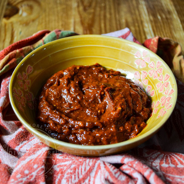 K'uut Bi Ik (Dried Chili Salsa) made with morita chipotles in a small yellow bowl on a bunched up patterned cloth