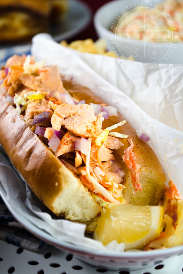 Salmon Guédille with coleslaw in a lobster roll bun, served with chips and a lemon wedge