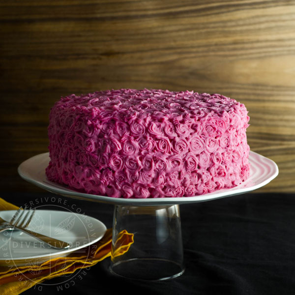 Chocolate cake made with beetroot and candied pecans, frosted with pink cream cheese frosting rosettes