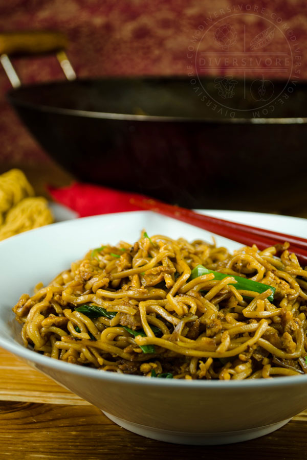 Chinese soy sauce fried noodles with red chopsticks in a white bowl