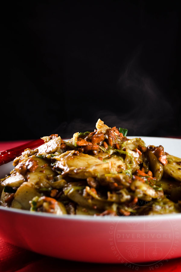 Steam rising from a bowl of salmon fried rice cakes (chao nian gao) against a black backdrop