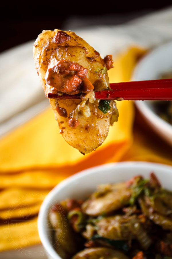 Red chopsticks holding a fried rice cake (chao nian gao) with salmon