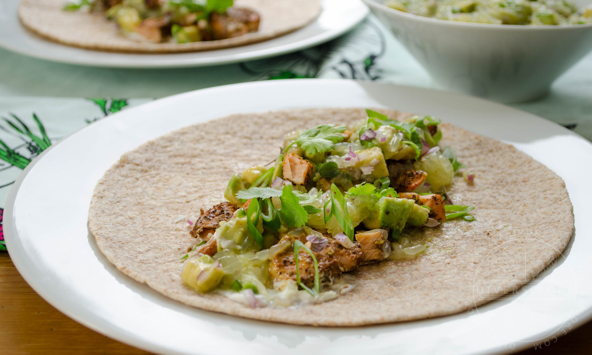 Broiled fish tacos with avocado-grapefruit salsa served in a whole wheat tortilla on a white plate