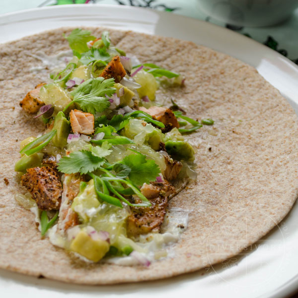 Broiled fish tacos with avocado-grapefruit salsa served in a whole wheat tortilla on a white plate