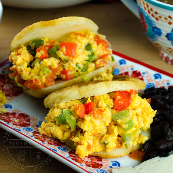 Perico served in arepas with black beans on a colourful rectangular plate